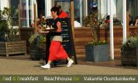 serveester in traditionele visserskledij aan tearoom het zand op de zeedijk van oostduinkerke